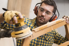 A carpenter is Sanding a wooden workpiece.